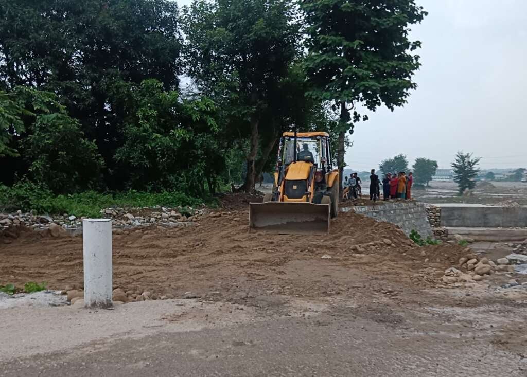 सुरक्षा दीवार निर्माण के चलते बाधित मार्ग पर बना कच्चा रास्ता, 15 दिन में पक्की सड़क का निर्माण पूरा करने का आश्वासन